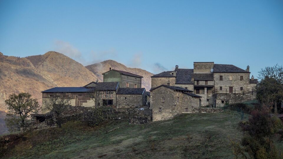 Un casale di pietra, con le montagne dietro